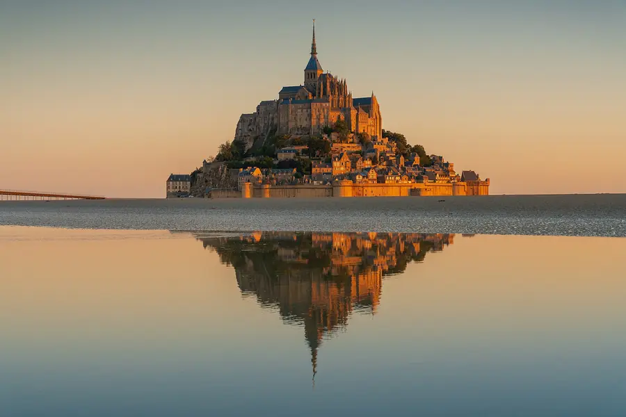 Mont Saint-Michel reflected in still water at sunrise