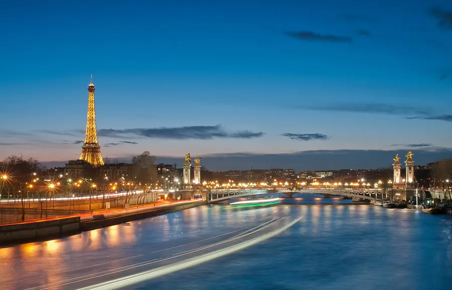 The Eiffel Tower and Pont Alexandre III lit up over the Seine at night